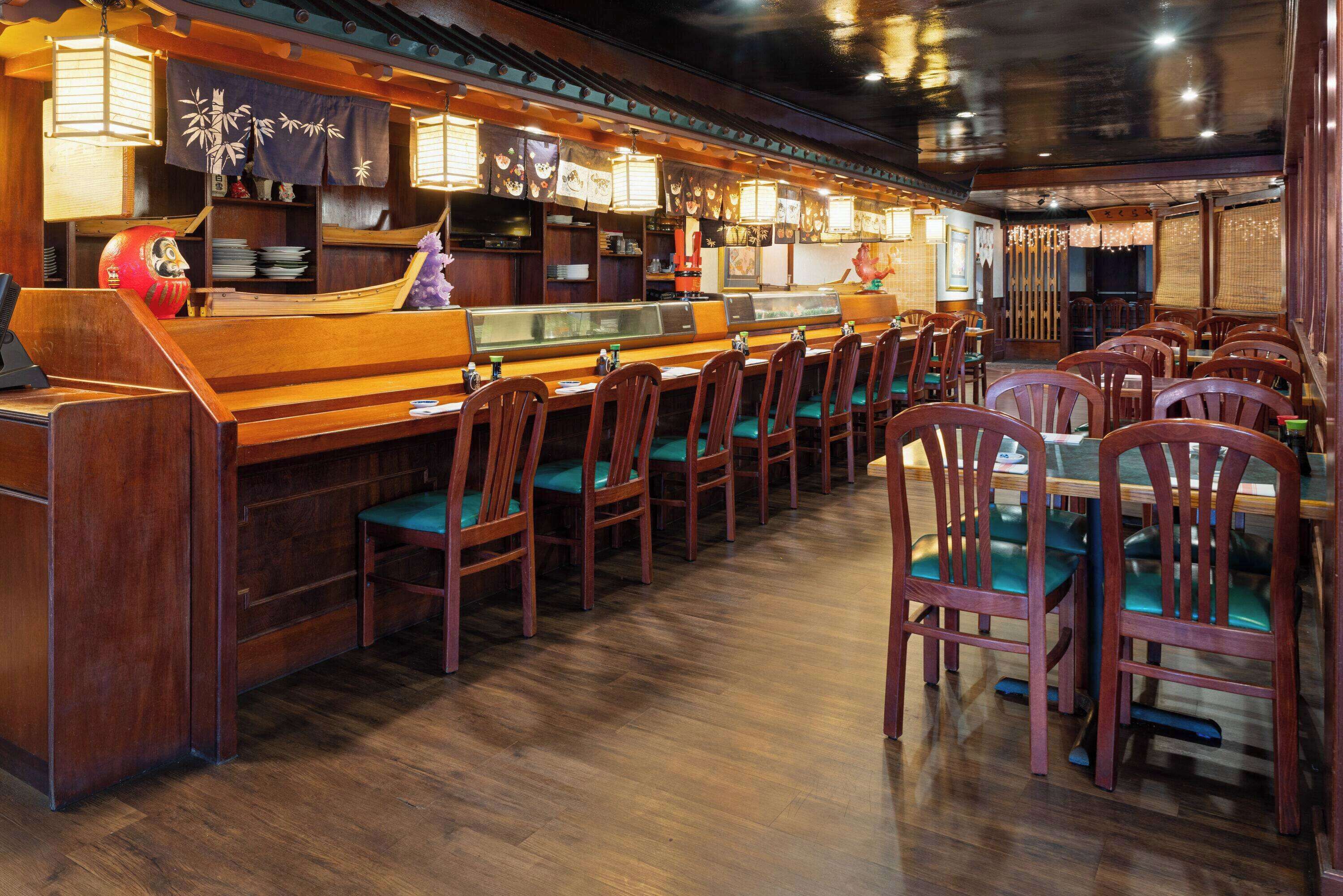 A restaurant with wooden booths and tables, a sushi bar, and traditional decor.
