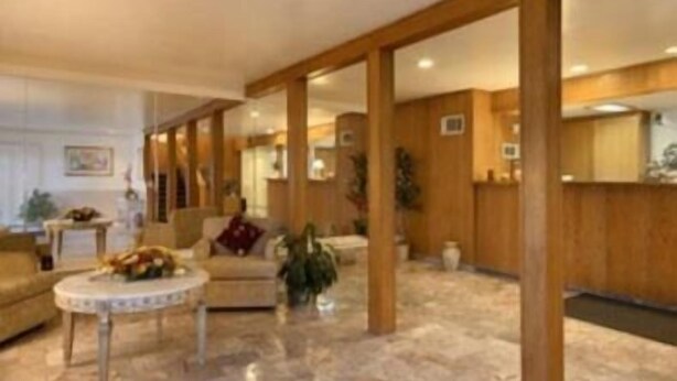 A spacious lobby with a marble floor, wooden columns, and a seating area with a round table and chairs. - Merced Inn and Suites (Merced)