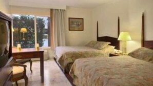 A hotel room with two beds, a desk, a chair, a television, and a window with curtains. - Merced Inn and Suites (Merced)