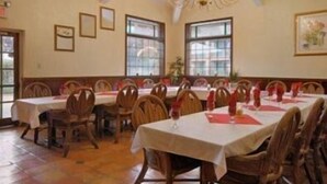 A dining room with wooden chairs and tables, a chandelier, and framed pictures on the walls. - Merced Inn and Suites (Merced)