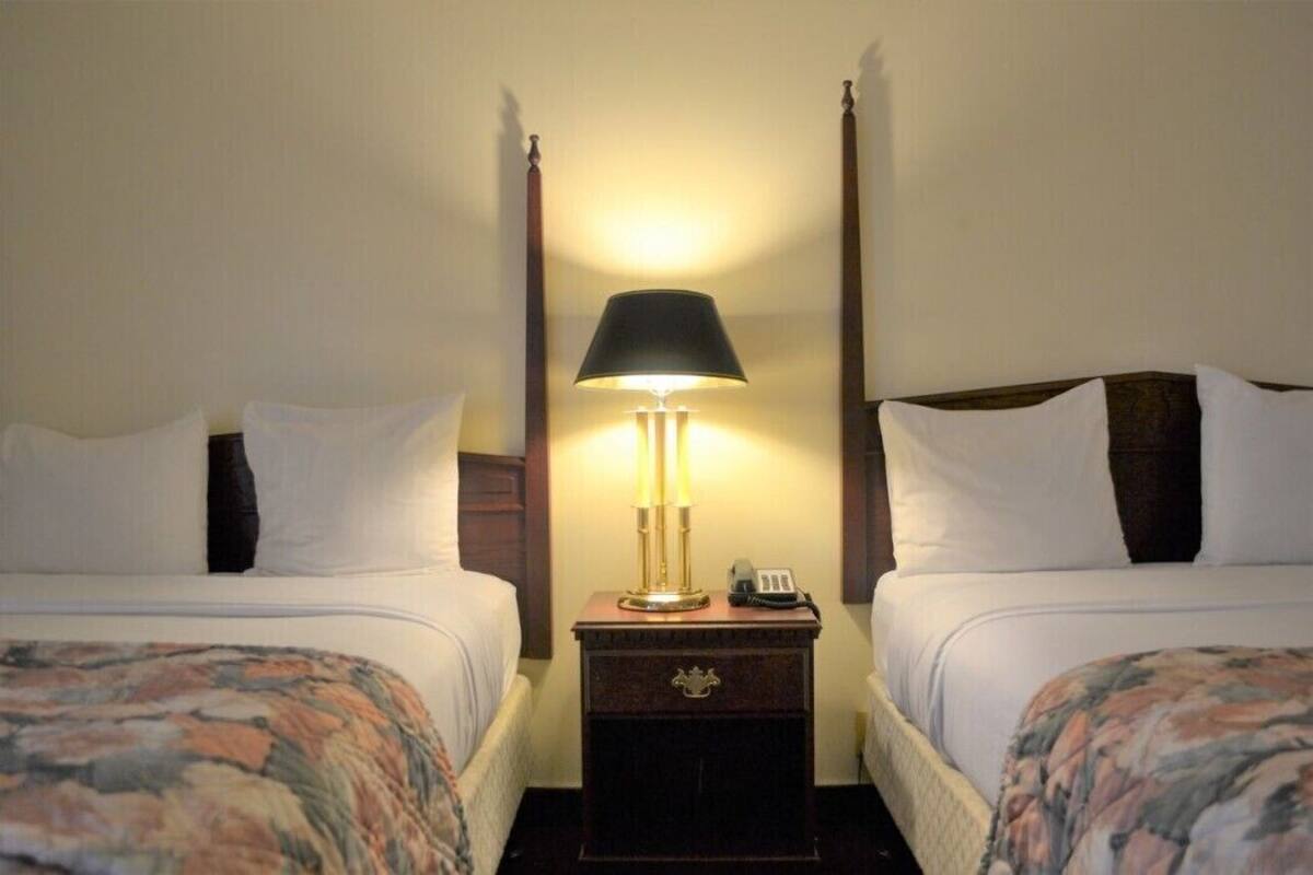 A double room with two beds, a nightstand with a lamp, and a telephone.