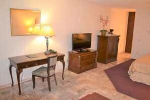 Relax in a cozy space with a comfortable bed, desk, and TV.