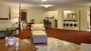 A living room with a sofa, armchairs, a coffee table, and a dining area with a chair and table. - Merced Inn and Suites (Merced)