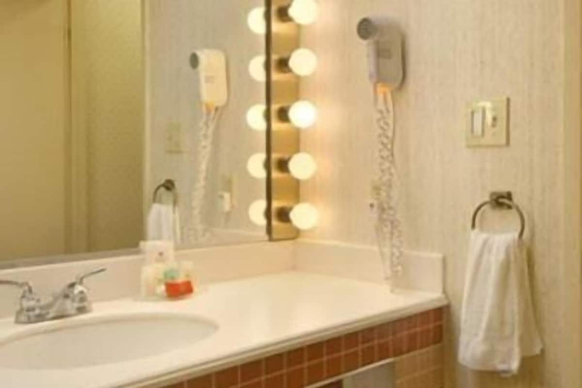 A bathroom with a sink, mirror, and lights.
