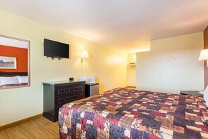 Una habitación de hotel con una cama, un aparador, un televisor y una lámpara.