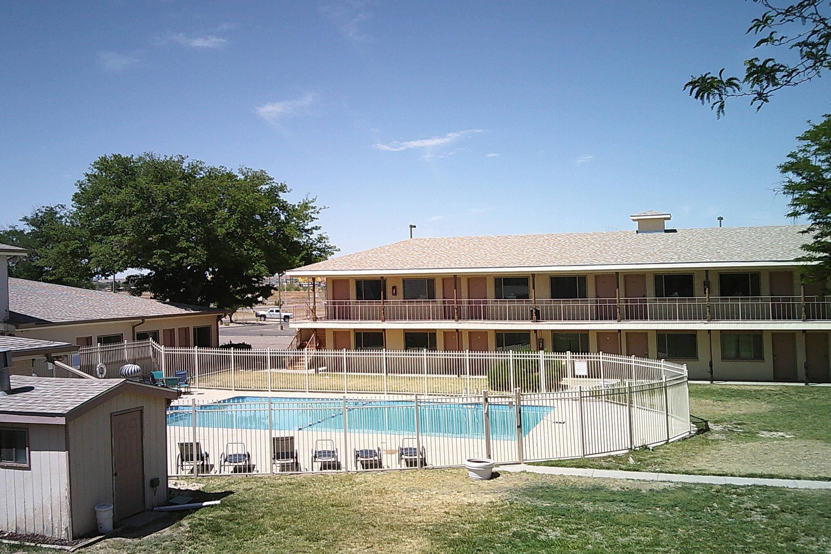 A motel with a swimming pool, fenced yard, and a two-story building.