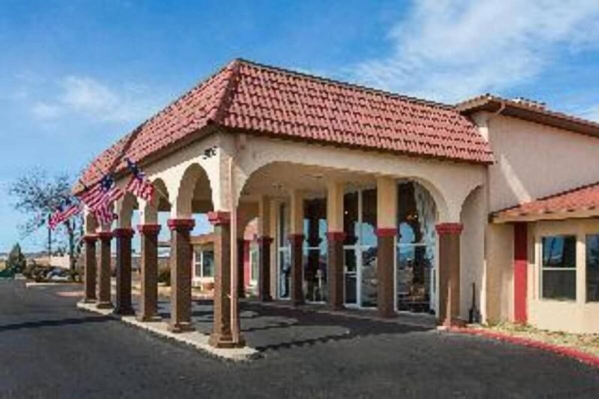 A building with a red-tiled roof, multiple arches, and a flag.
