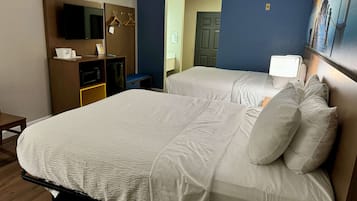 A hotel room with two beds, a television, a microwave, and a small seating area.