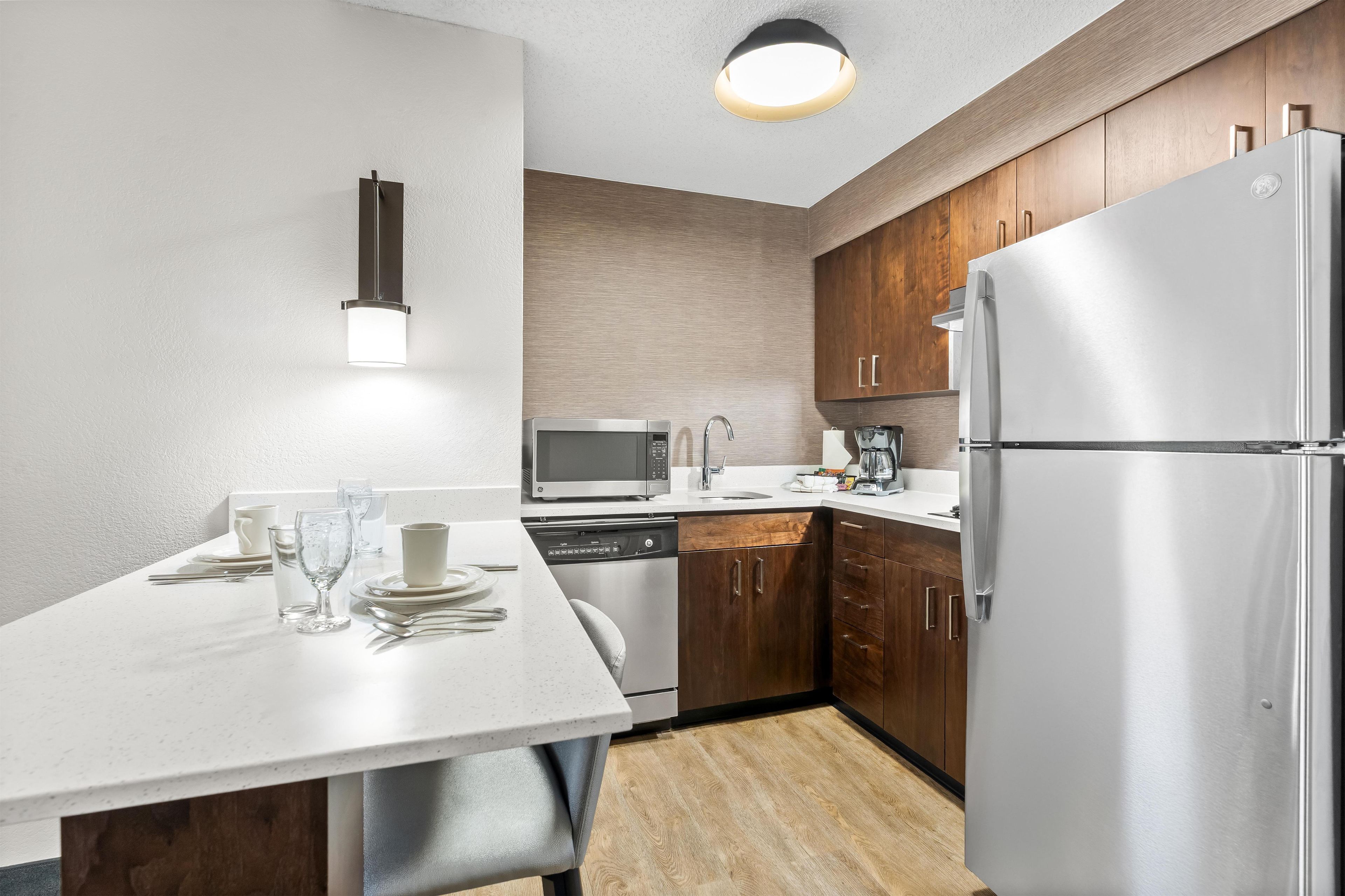 A modern kitchen with a white countertop, stainless steel appliances, and wooden cabinets.