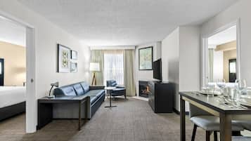 Ett hotellrum med en soffa, ett matbord, en TV och en öppen spis.