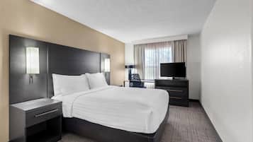 Une chambre d’hôtel avec un lit, des tables de chevet, une télévision et une fenêtre avec des rideaux.