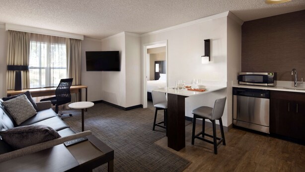 Una habitación de hotel moderna con sala de estar, comedor y cocina.