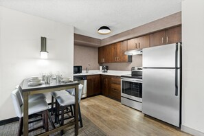 Una cocina moderna con electrodomésticos de acero inoxidable, armarios de madera y un comedor con mesa y sillas.