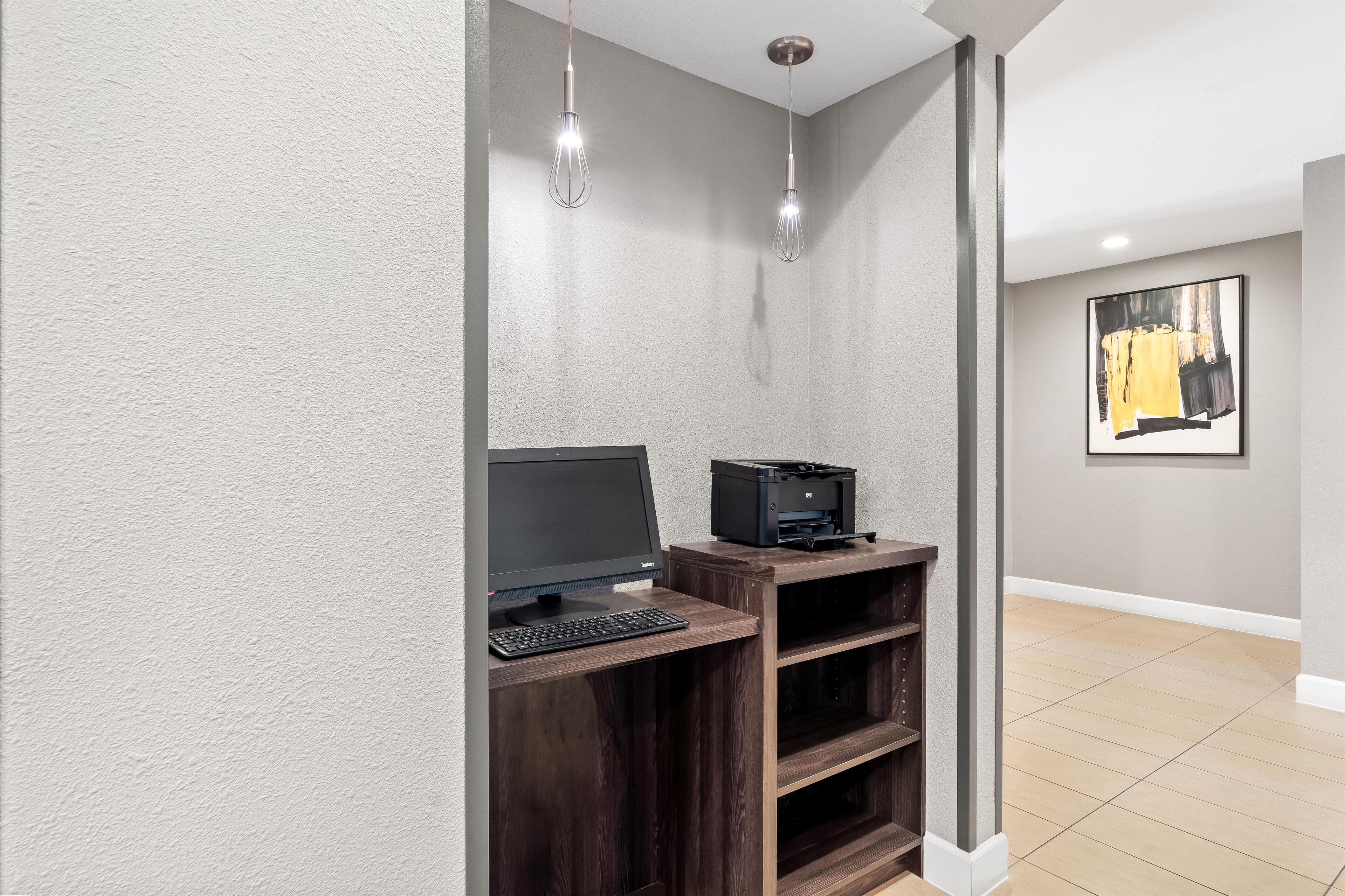 A modern office space with a desktop computer, a printer, and a pendant light fixture.
