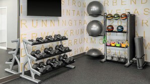 A gym with a wall-mounted TV, dumbbells, kettlebells, and a weight rack. - Residence Inn by Marriott Mystic Groton (Mystic)