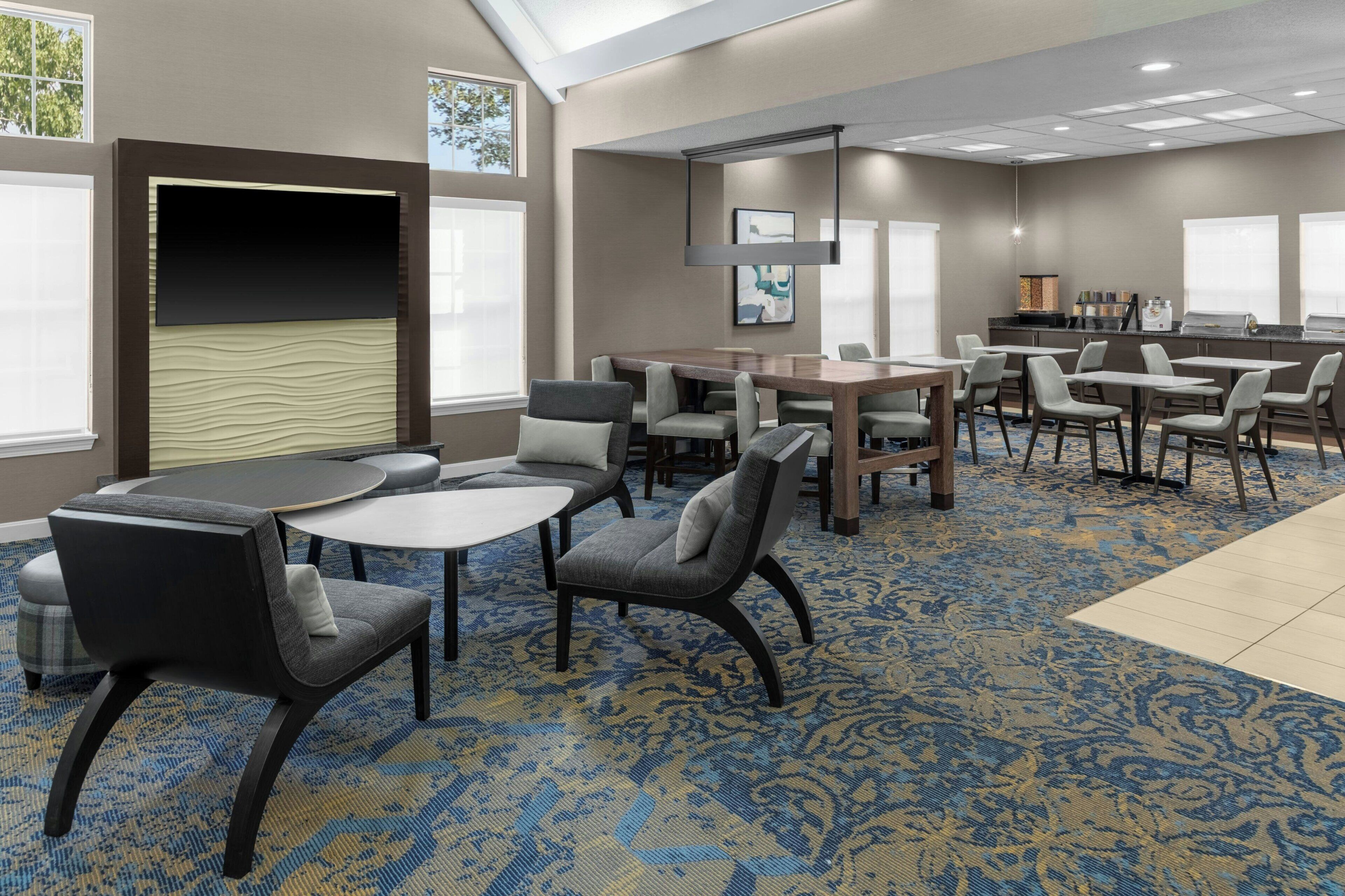 A hotel room with a large bed, a desk, and a seating area with chairs and tables.