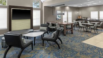 A hotel room with a large bed, a desk, and a seating area with chairs and tables.