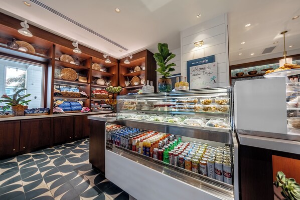 A breakfast bar with a variety of food items and beverages, wooden shelves with baskets, and a welcome sign. - Lido Beach Resort (Sarasota)
