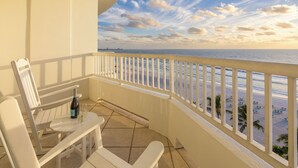 A balcony with white chairs and a table, overlooking a beach with palm trees and a clear sky. - Lido Beach Resort (Sarasota)