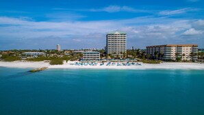 A coastal hotel with multiple buildings, a beach with sun loungers, and clear blue waters. - Lido Beach Resort (Sarasota)