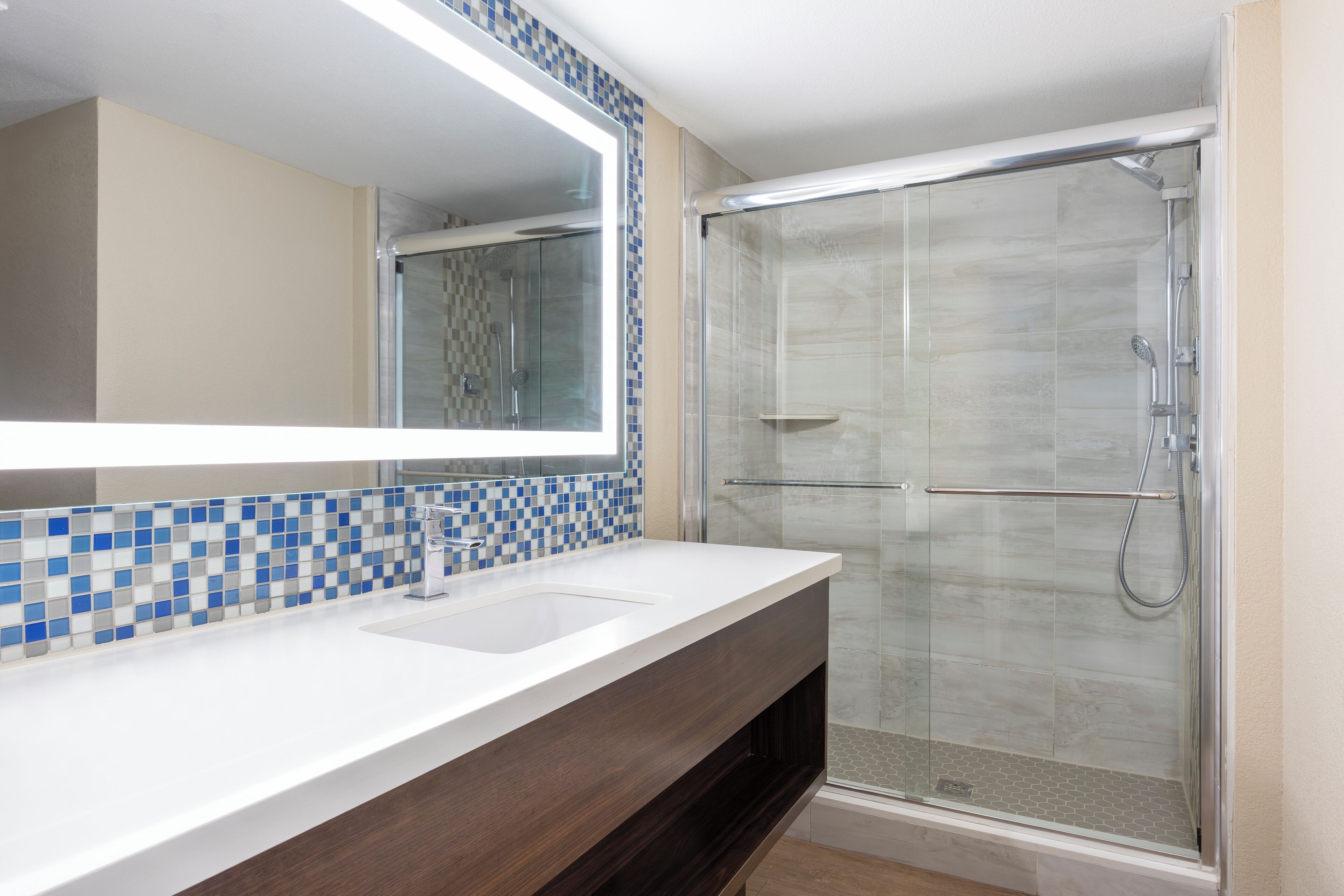 A bathroom with a white sink, a mirror, and a glass-enclosed shower.