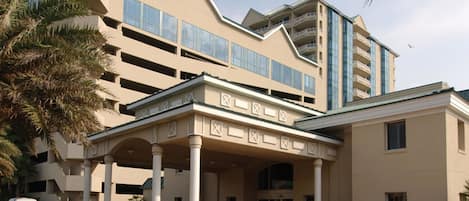 A multi-story hotel with a central courtyard, columns, and a parking area.