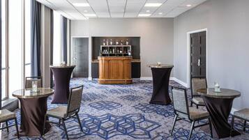 Een hotel lobby met een bar, ronde tafels en stoelen.