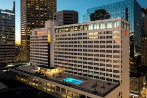 A Sheraton hotel with a rooftop pool, surrounded by high-rise buildings.