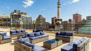 Una terrazza sul tetto con mobili in vimini e uno skyline urbano sullo sfondo.