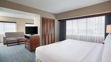 A hotel room with a bed, a television, a desk, a chair, and a wardrobe.
