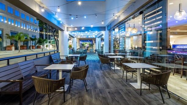 A modern indoor dining area with wooden flooring, tables, and chairs. - Crowne Plaza Los Angeles Harbor Hotel by IHG (San Pedro)