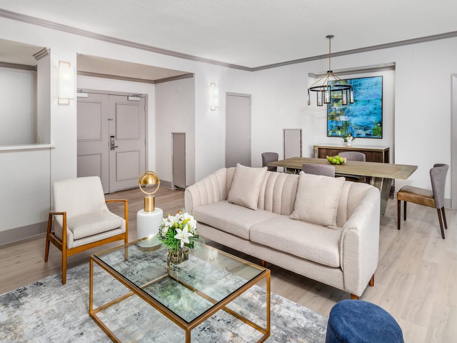 Un salon moderne comprenant un canapé, un fauteuil, une table basse en verre et un coin repas avec une table et des chaises.