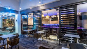 An indoor dining area with tables and chairs, a bar area with a counter, and hanging pendant lights. - Crowne Plaza Los Angeles Harbor Hotel by IHG (San Pedro)
