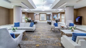 A spacious lobby with a central seating area, a reception desk, and a digital information kiosk. - Crowne Plaza Los Angeles Harbor Hotel by IHG (San Pedro)