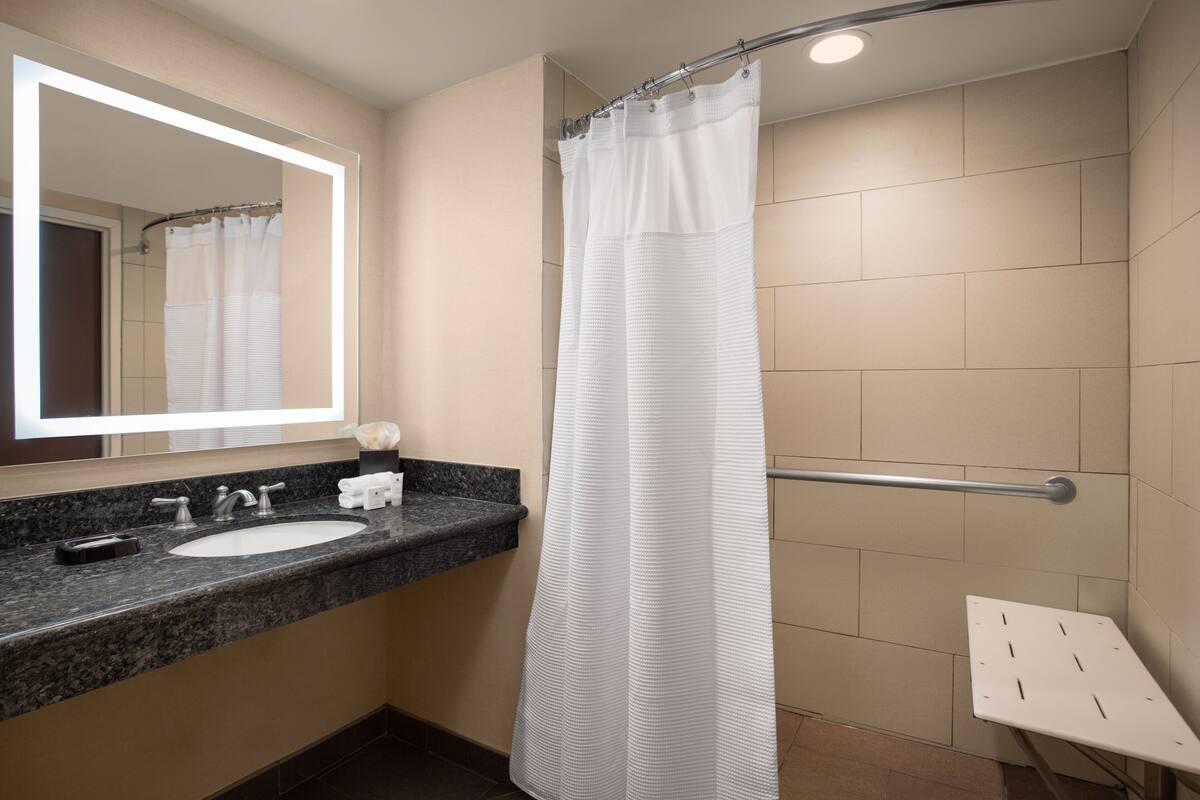 A bathroom with a sink, mirror, and shower curtain.