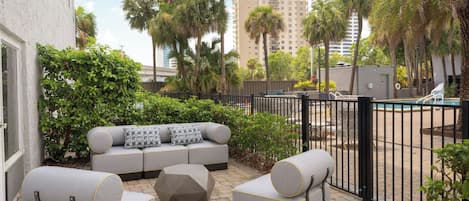A patio area with a gray sofa set, two armchairs, and a geometric coffee table.