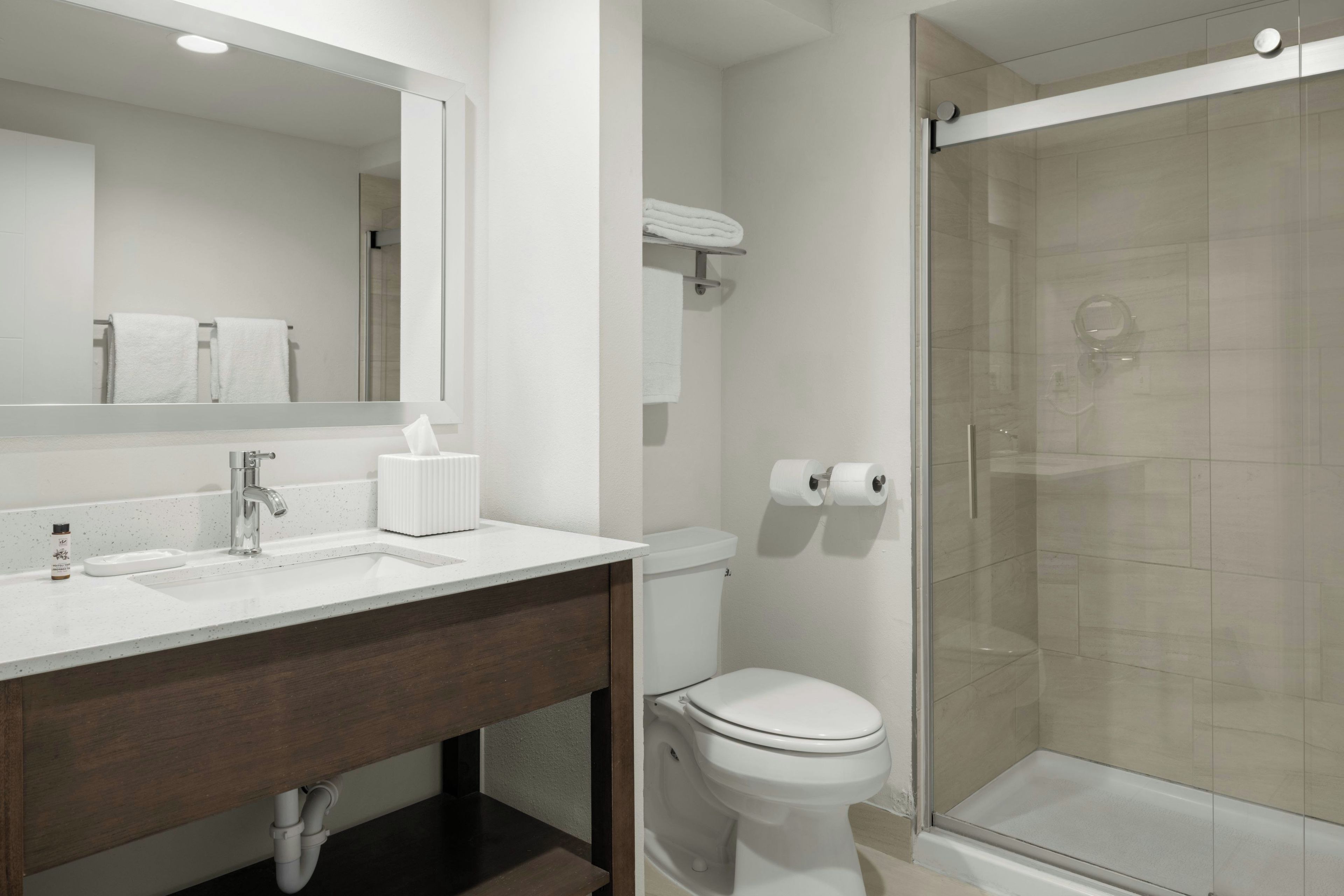Un baño moderno con lavamanos, espejo y retrete blancos.
