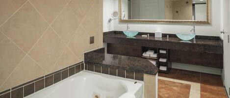 A modern bathroom with a bathtub, two sinks with glass bowls, a large mirror, and a towel rack.
