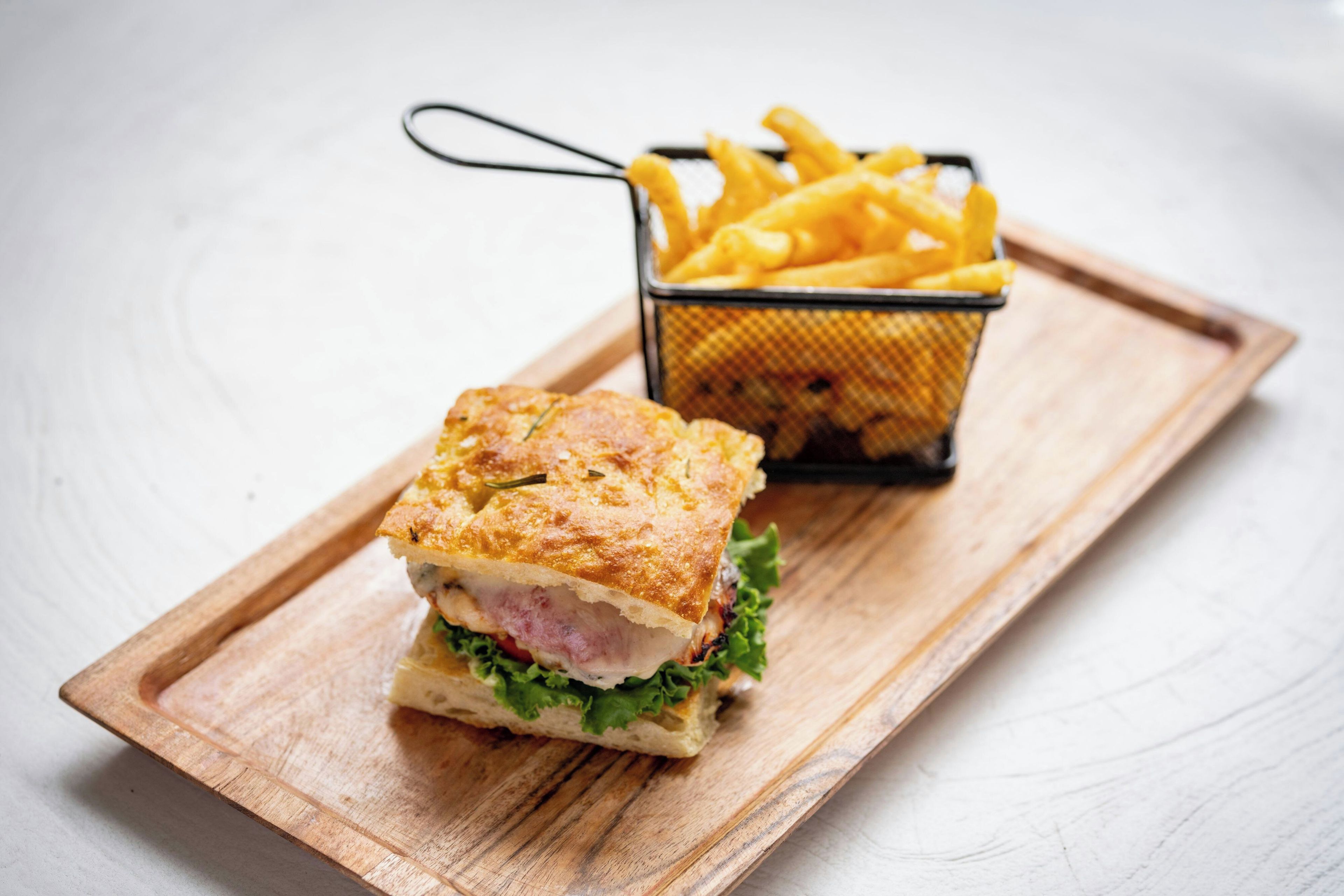 A sandwich with a side of fries on a wooden board.