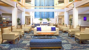 A spacious lobby with a central seating area, multiple levels, and a sales office in the background. - Southbank Hotel by Marriott Jacksonville Riverwalk (Jacksonville)