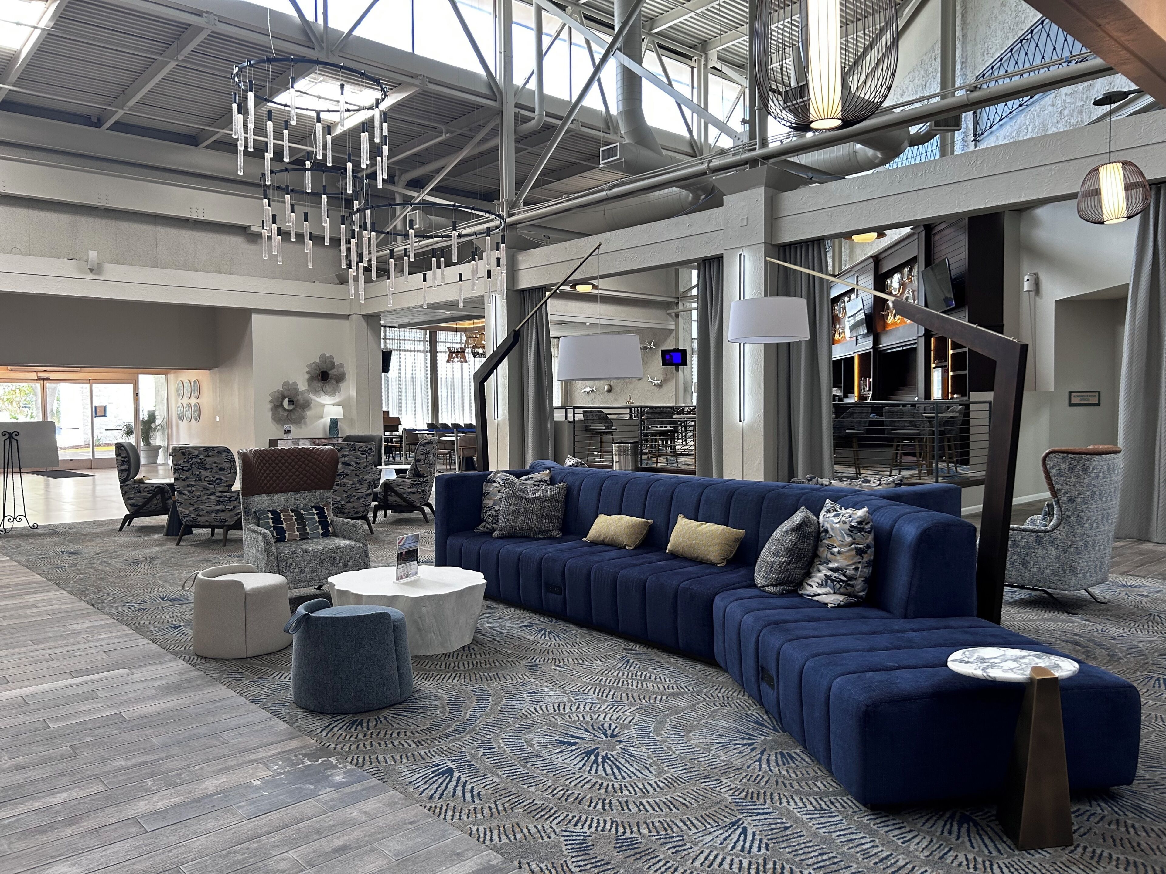 Un amplio espacio de sala con un sofá modular azul, alfombra estampada y lámparas modernas.