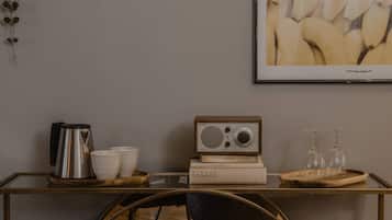 A modern room with a glass table displaying a radio, books, and a tray with glasses.
