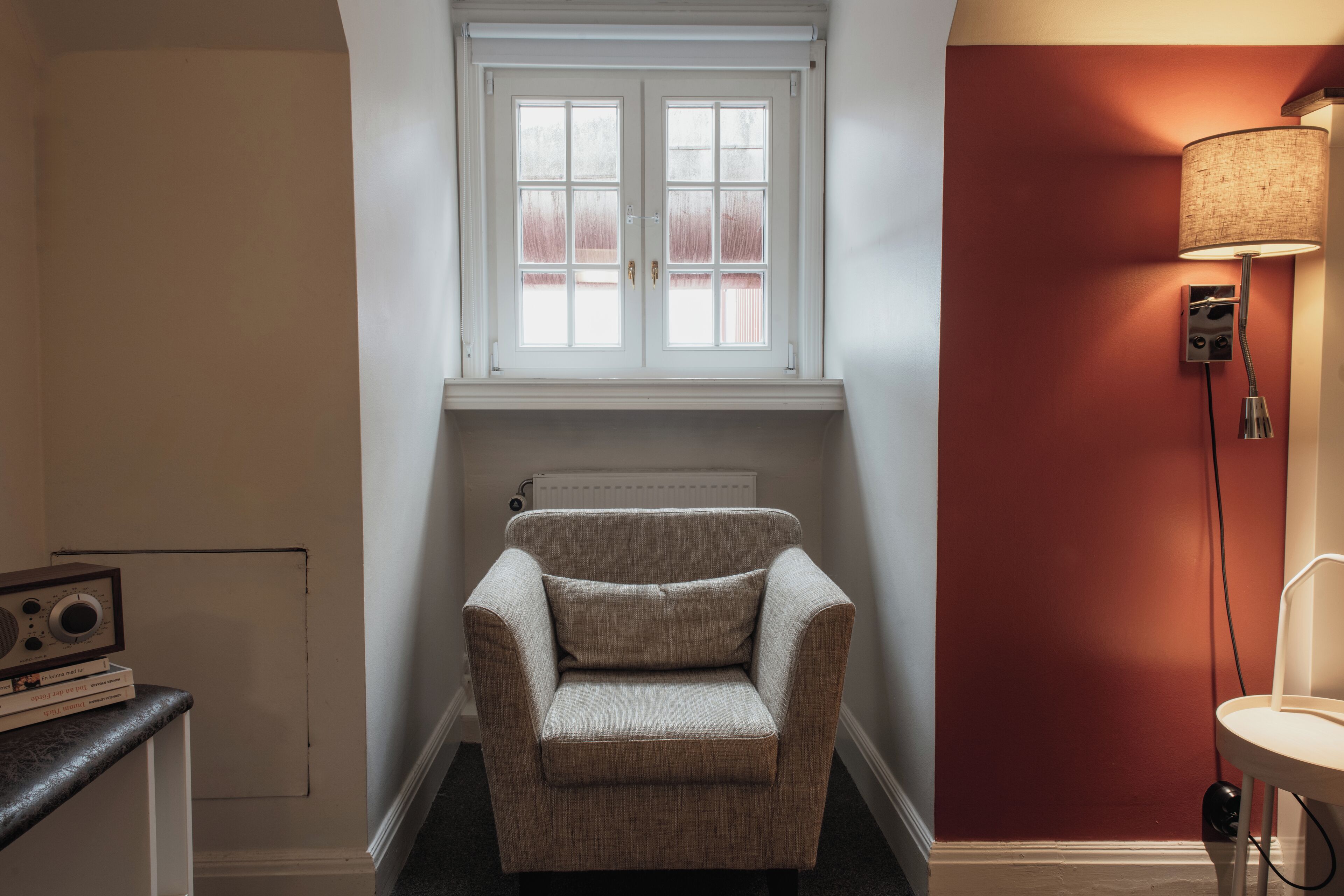 A corner room with a window, radiator, and a lamp.