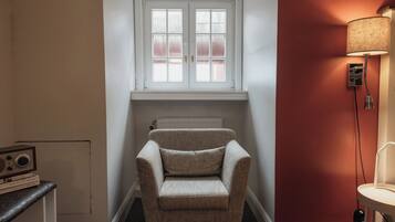 A corner room with a window, radiator, and a lamp.