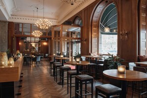 A spacious hotel lobby with wooden flooring, multiple seating areas, and a large arched window. - Home Hotel Grand, Helsingborg (Helsingborg)