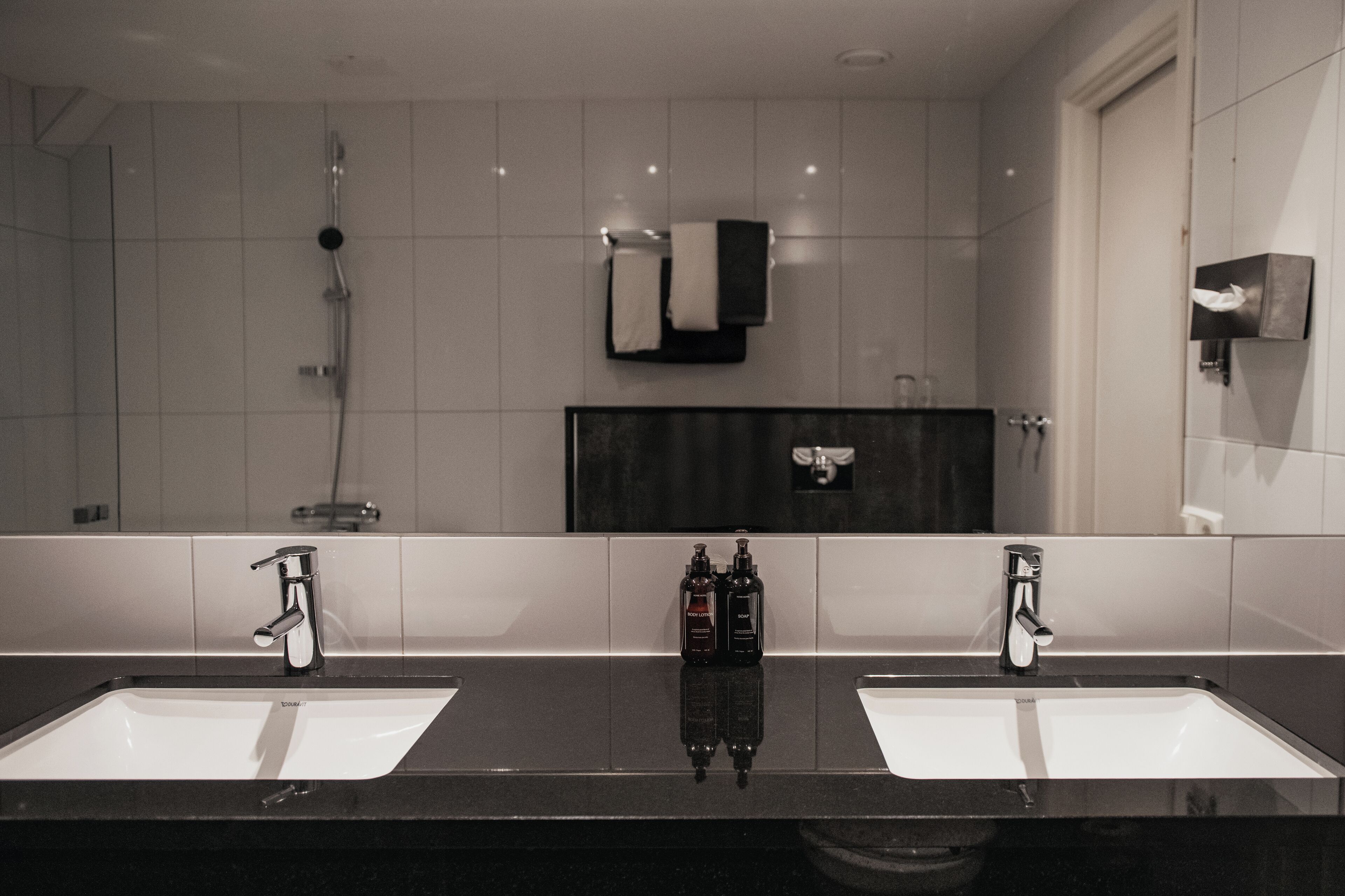 Un baño moderno con dos lavamanos, una ducha y un espejo.