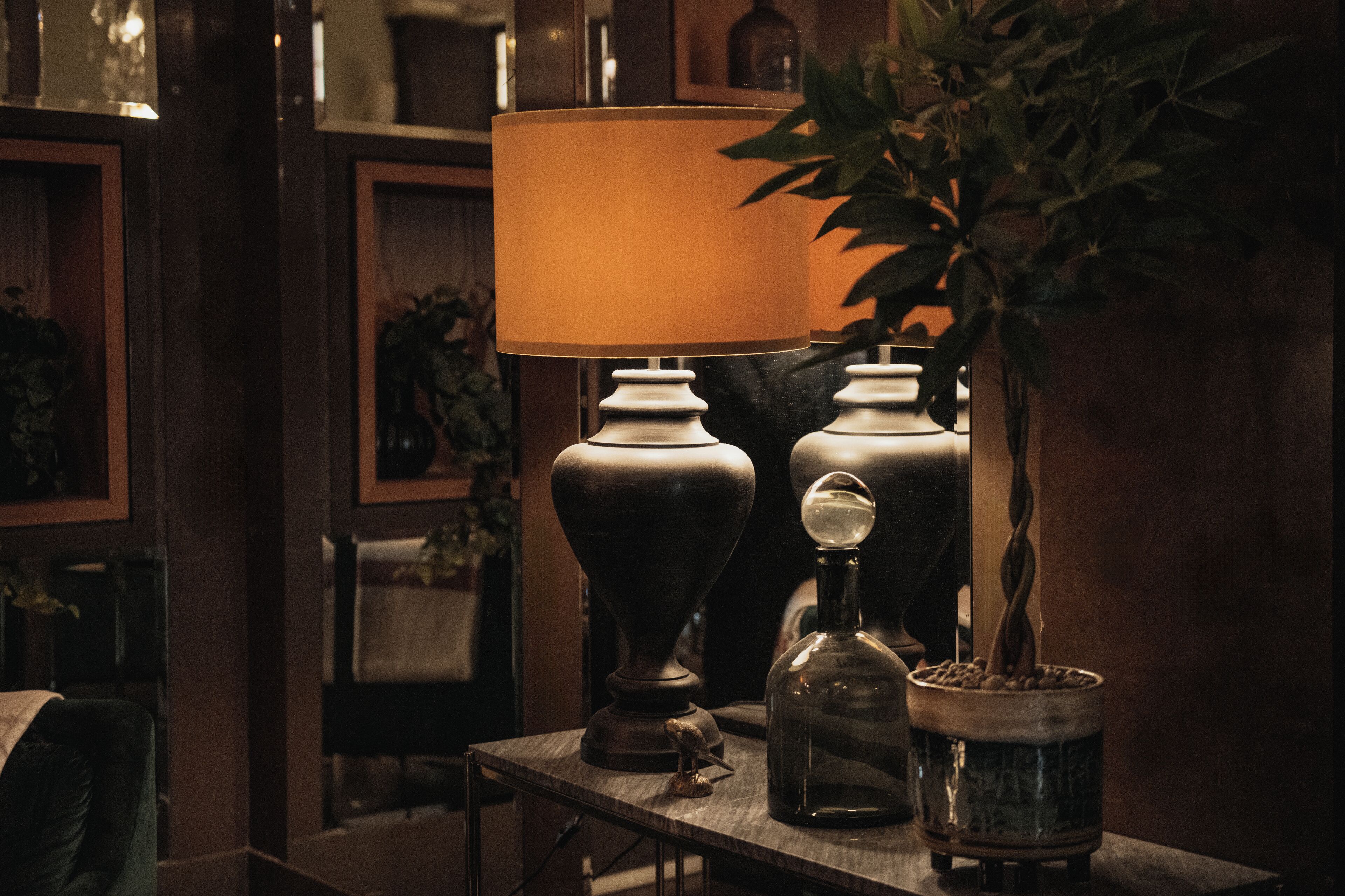 A table with a lamp, a bottle, and a potted plant.