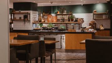En modern restaurang med en central ö, ett sittområde och dekorativa växter.