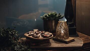 Una mesa de madera con un plato de brownies, una suculenta en maceta y un candelabro decorativo.