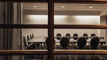 Una sala de conferencias con una larga mesa y varias sillas, vista a través de una ventana con marcos de madera.